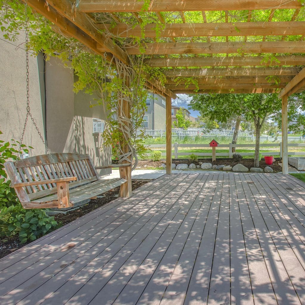 Swing Hanging On A Pergola Covering A Wooden Deck